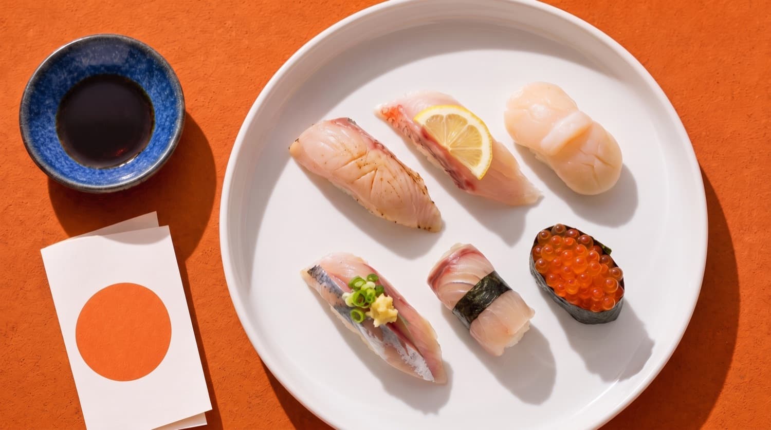 A second course of six nigiri on a wide rice-white plate